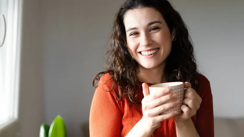 Gut gelaunte Frau trinkt einen Kaffee.