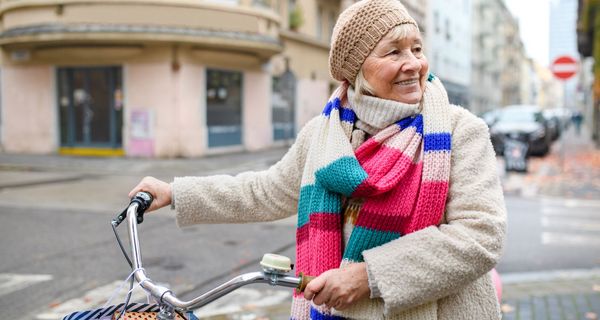 Ältere Frau mit dem Fahrrad in der Stadt.