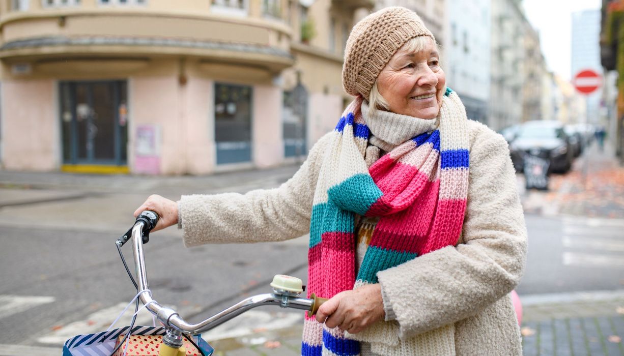 Ältere Frau mit dem Fahrrad in der Stadt.