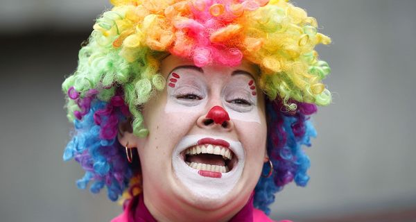 Eine Frau als Clown verkleidet mit bunter Perücke und Schminke.