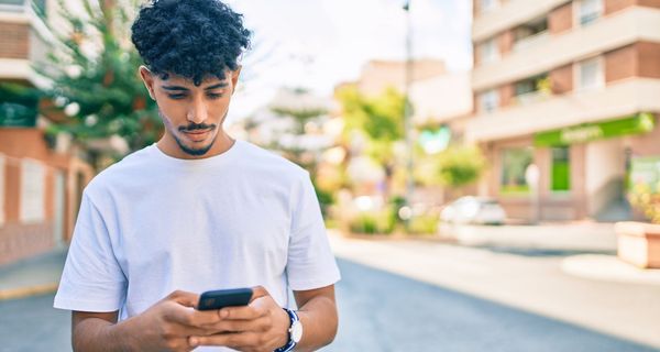 Junger Mann, schaut auf sein Smartphone.