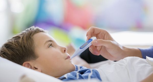 Kind mit einem Fieberthermometer im Mund.