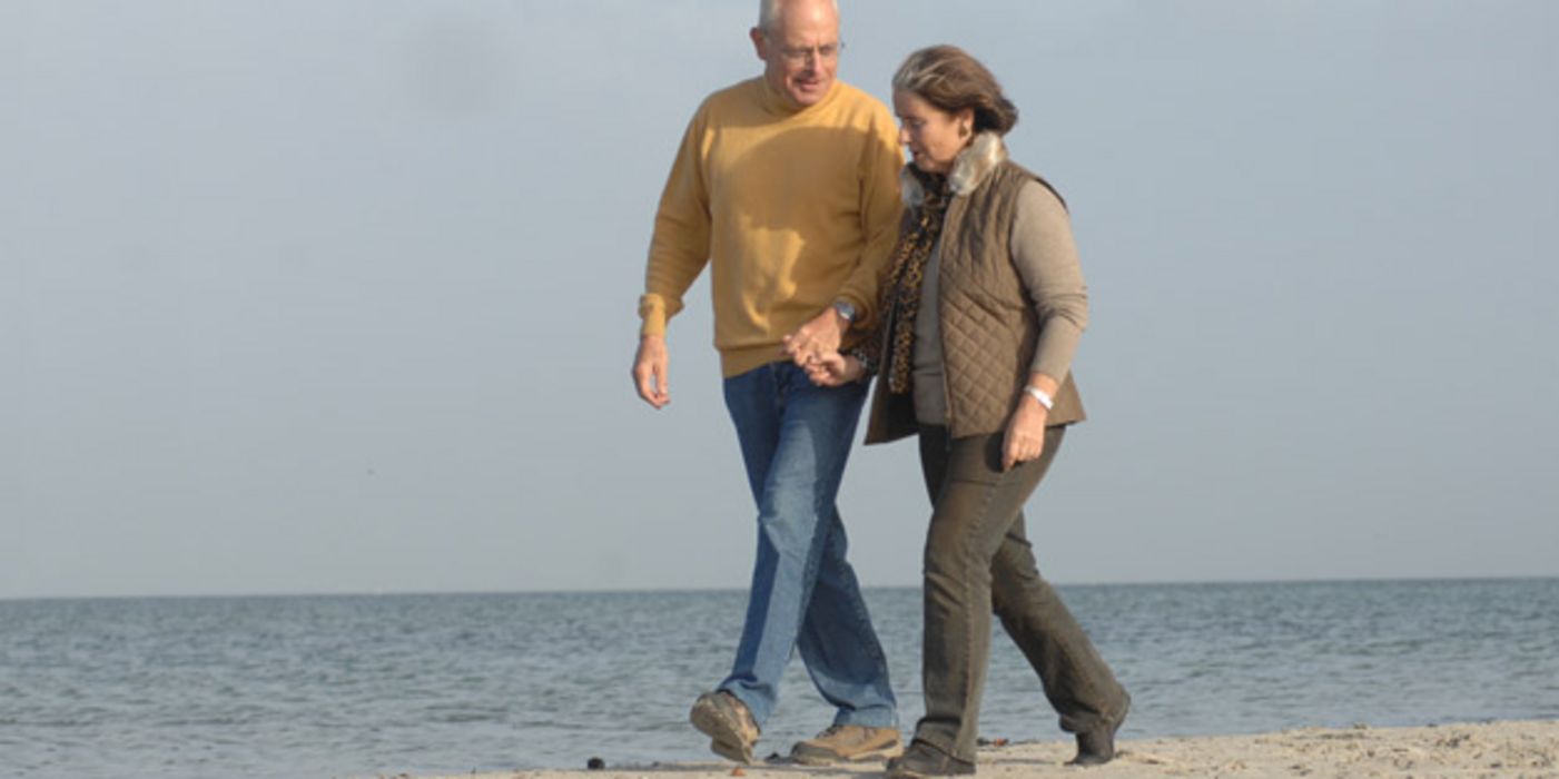 Seniorenpaar geht am Strand spazieren.