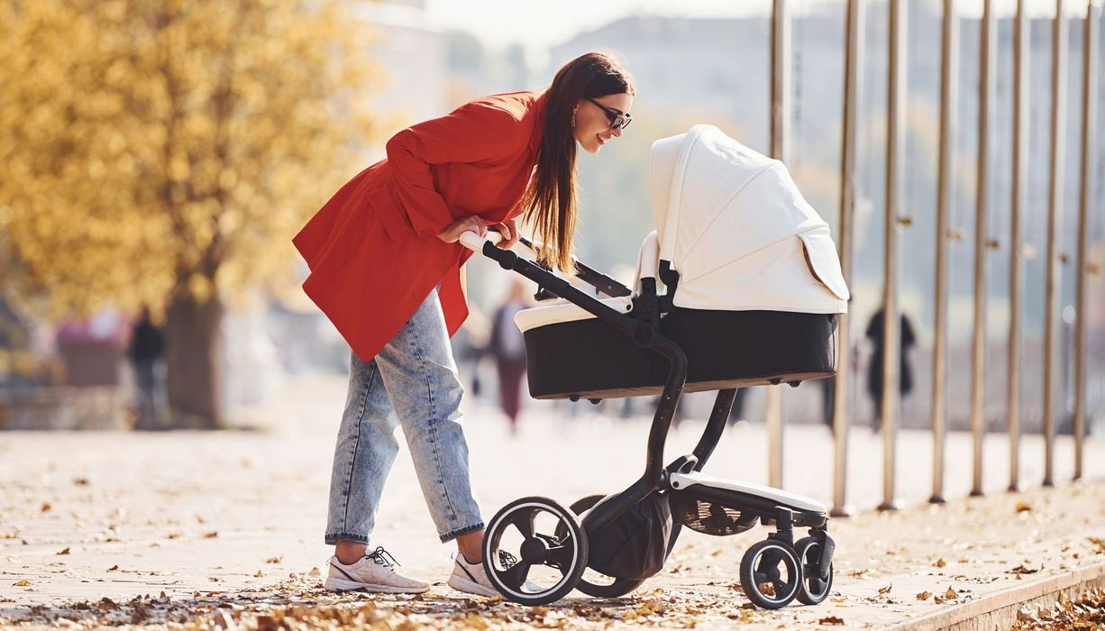 Junge Mutter, geht mit Kinderwagen spazieren.