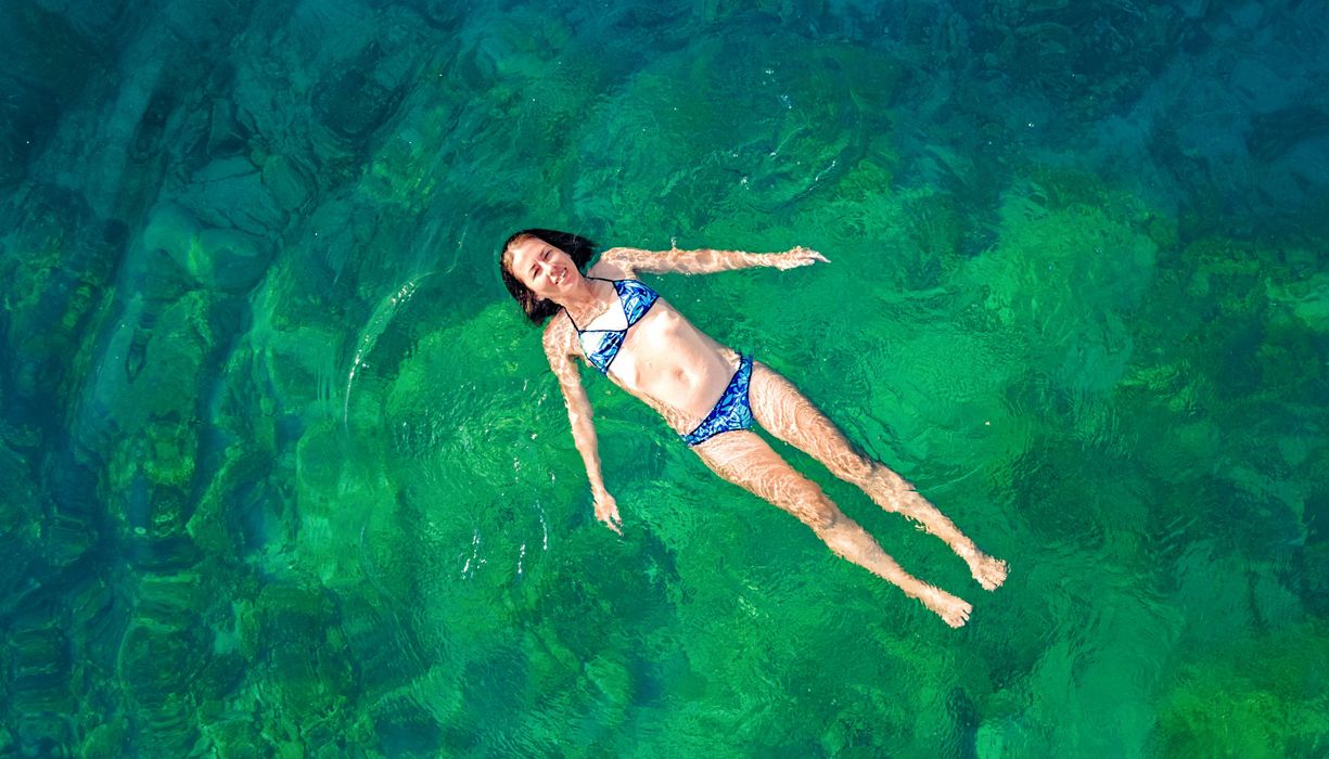 Junge Frau schwimmt rücklings im See.