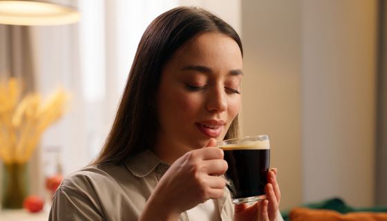 Junge Frau tritt eine Tasse Kaffee.