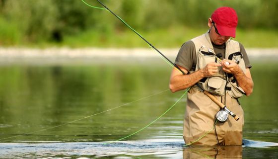 Ein Angler steht im Fluss und fischt