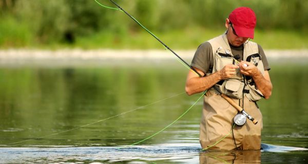 Ein Angler steht im Fluss und fischt