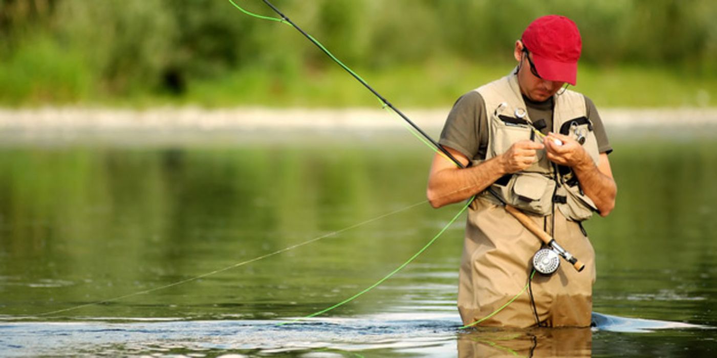Ein Angler steht im Fluss und fischt