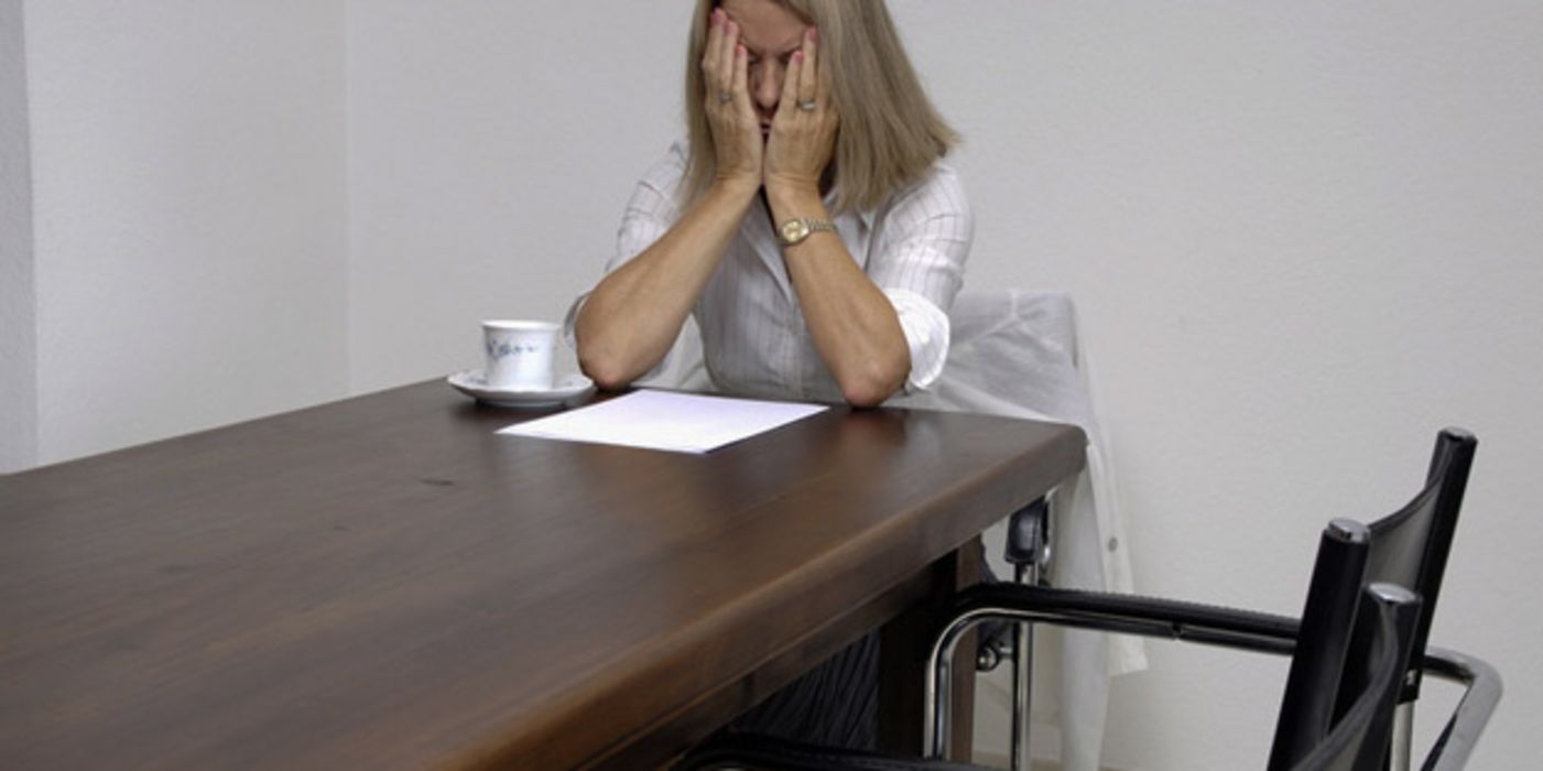 Frau sitzt allein im Konferenzraum.