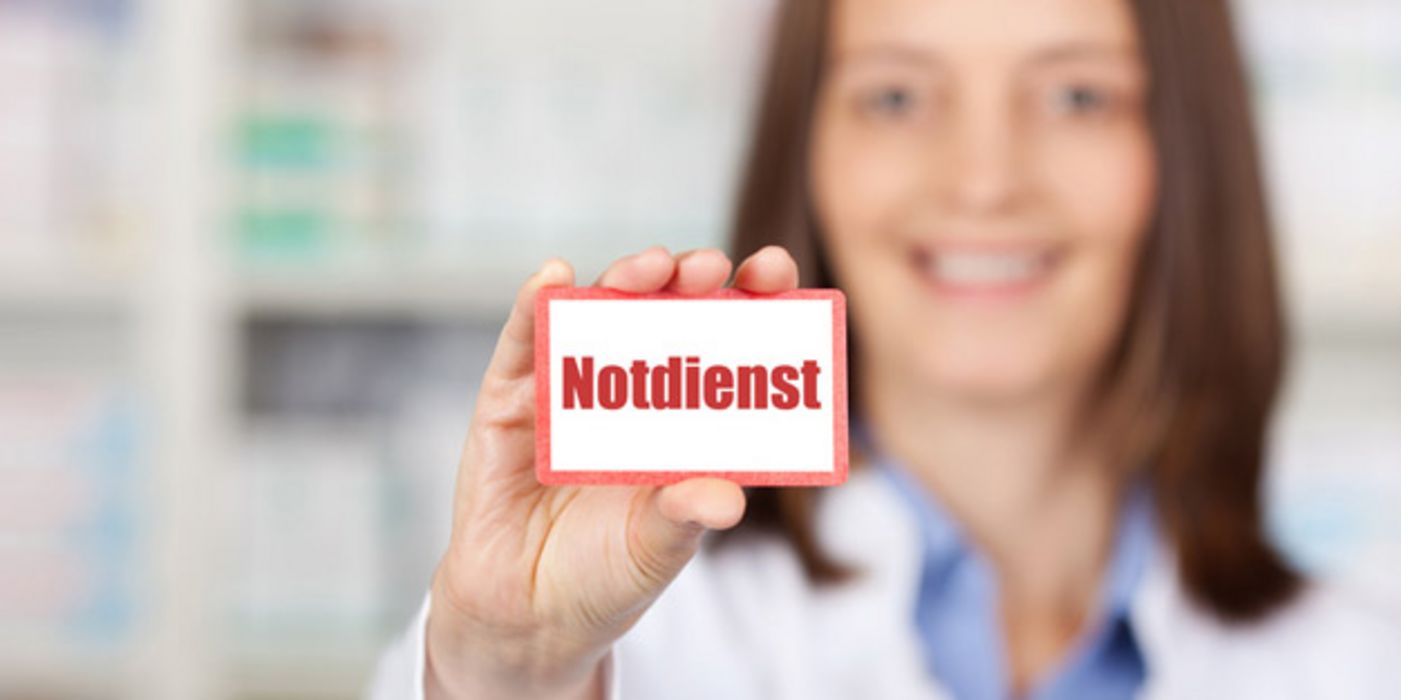 Apothekerin hält Notdienst-Schild in die Kamera.