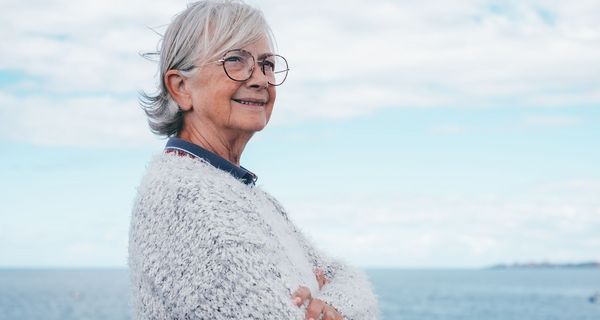 Ältere Frau, steht vor dem Meer.