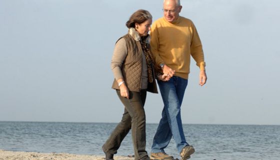 Älteres Pärchen geht am Strand spazieren