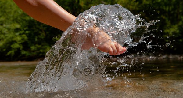 Frau, hält ihren Fuß ins Wasser.