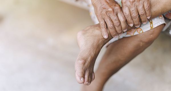 Älterer Frau, inspiziert ihren Fuß.