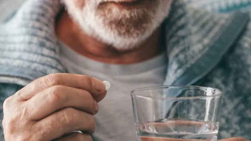 Älterer Mann, nimmt eine Tablette mit einem Glas Wasser.