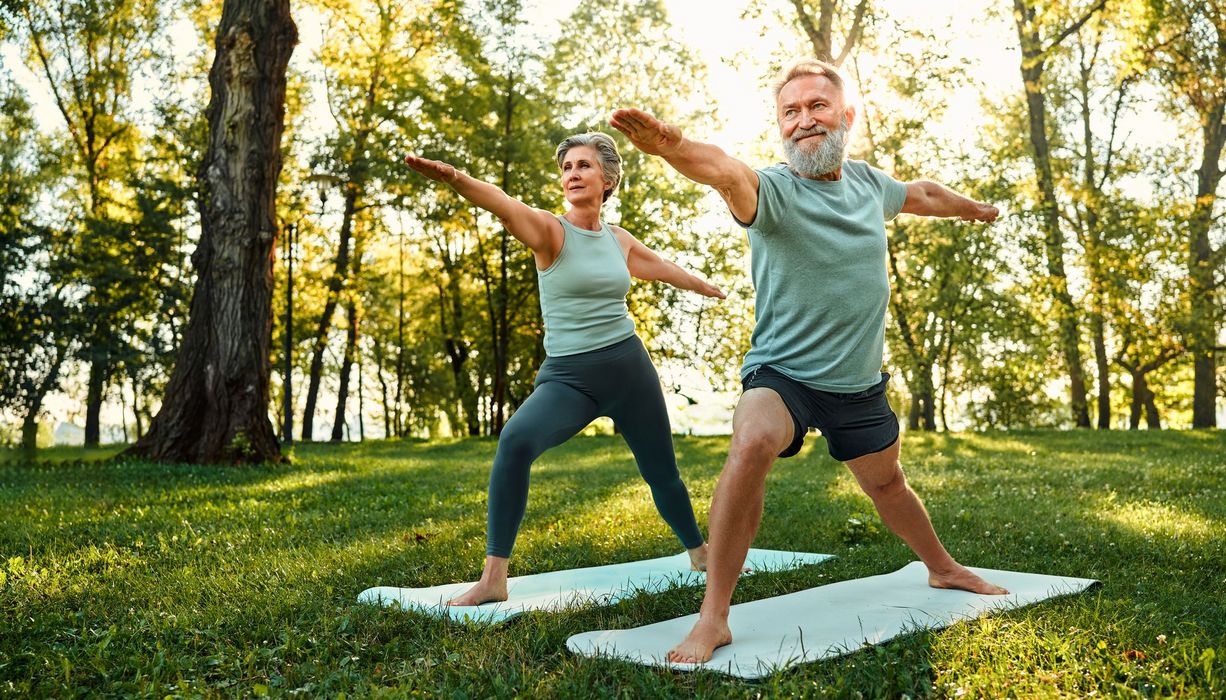 Zwei Senioren, trainieren Yoga im Park.
