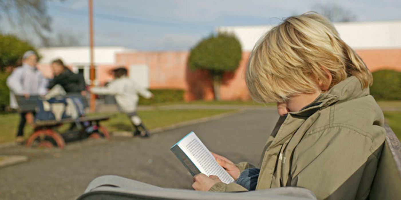 Einsamer Junge liest Buch.