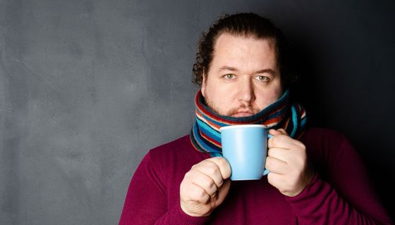 Mann mit Schal und Teetasse.