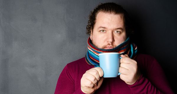 Mann mit Schal und Teetasse.