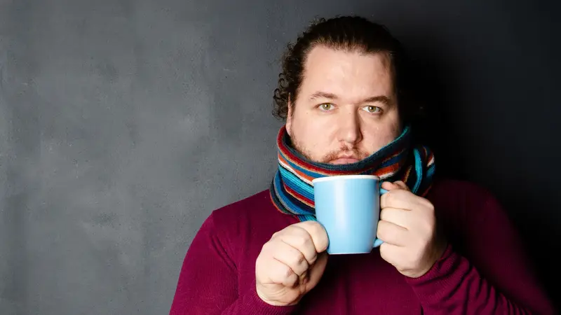 Mann mit Schal und Teetasse.