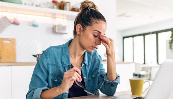 Frau vor dem Laptop hält sich die Stirn.