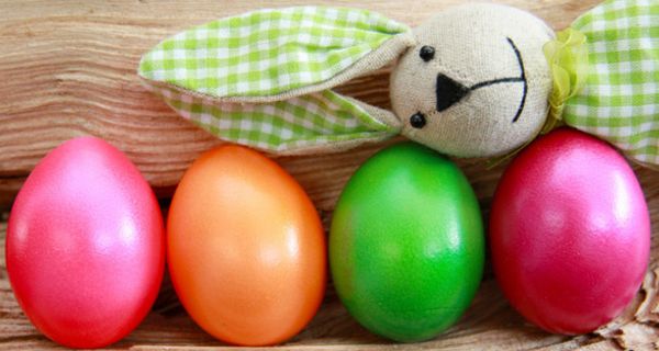Bunte Ostereier, quer obendrauf liegt ein Stoffosterhase