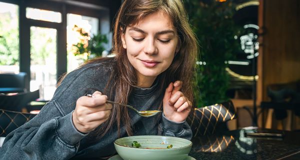 Junge Frau, löffelt Suppe.