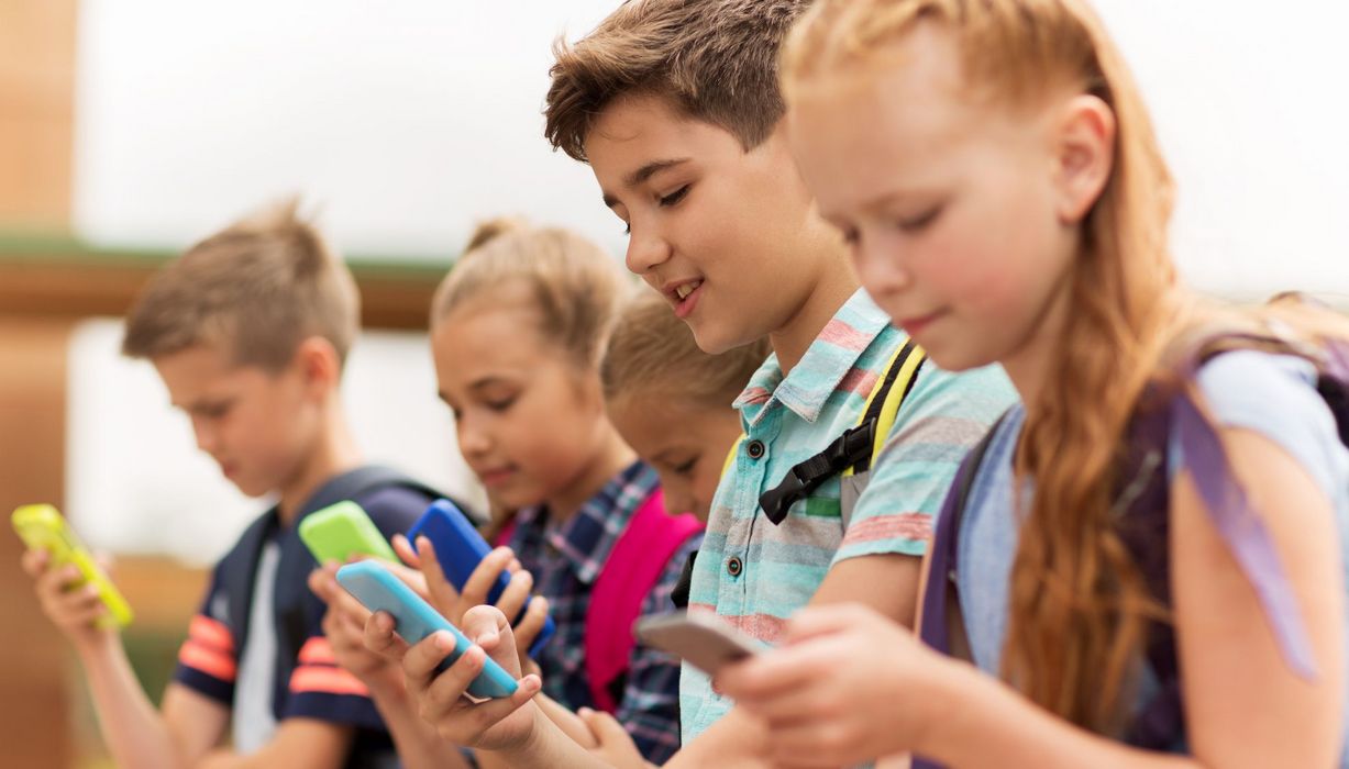 Grundschüler - Mädchen und Jungen - mit Smartphones in bunten Hüllen. 