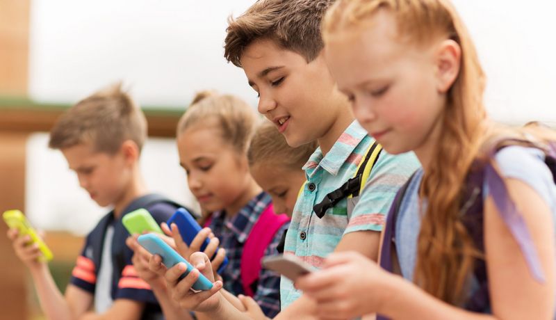 Grundschüler - Mädchen und Jungen - mit Smartphones in bunten Hüllen. 