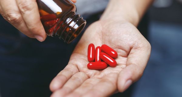 Rote Tabletten in der Hand einer Frau.