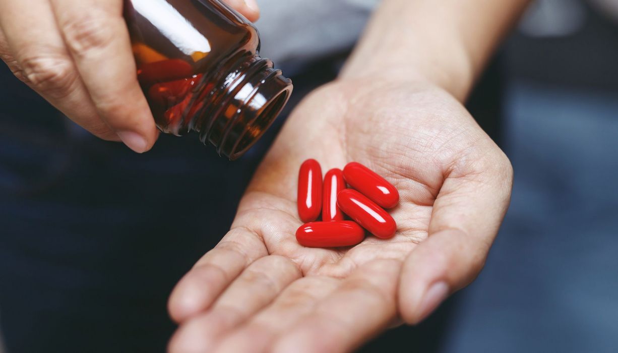 Rote Tabletten in der Hand einer Frau.