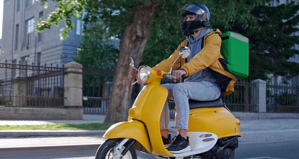 Ein Essens-Lieferdienst mit einem Motorroller.