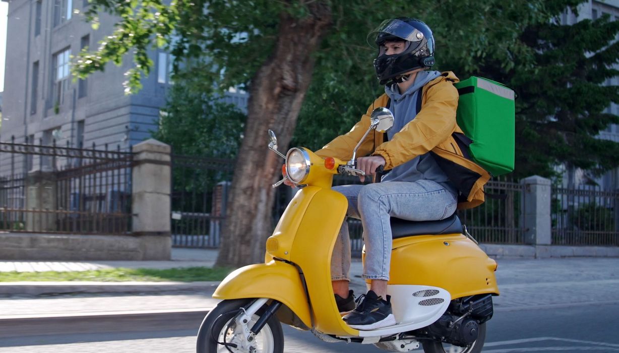 Ein Essens-Lieferdienst mit einem Motorroller.