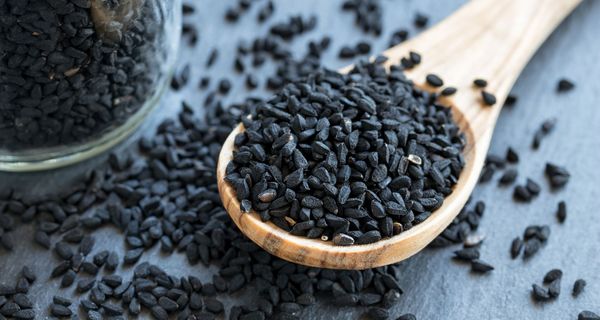 Holzlöffel, auf dem ein Haufen Schwarzkümmelsamen liegt.