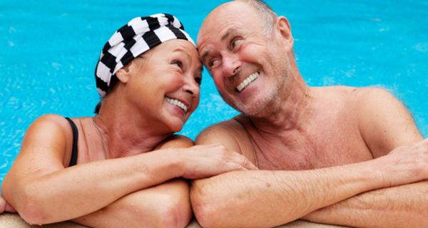 Zufriedenes Seniorenpaar am Rand eines Schwimmbadbeckens