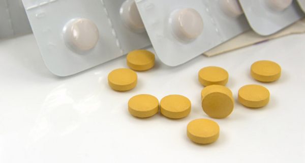 Gelbe Tabletten, im Hintergrund aufgestellt: Blisterpackungen