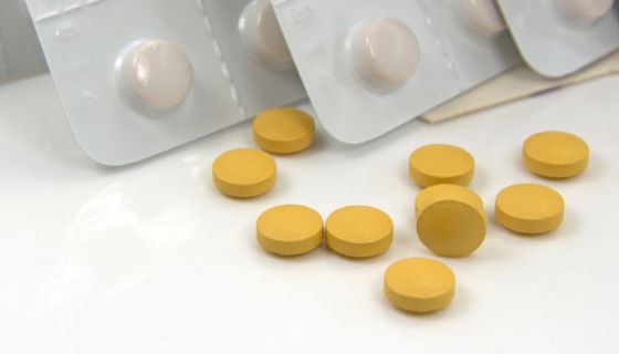 Gelbe Tabletten, im Hintergrund aufgestellt: Blisterpackungen