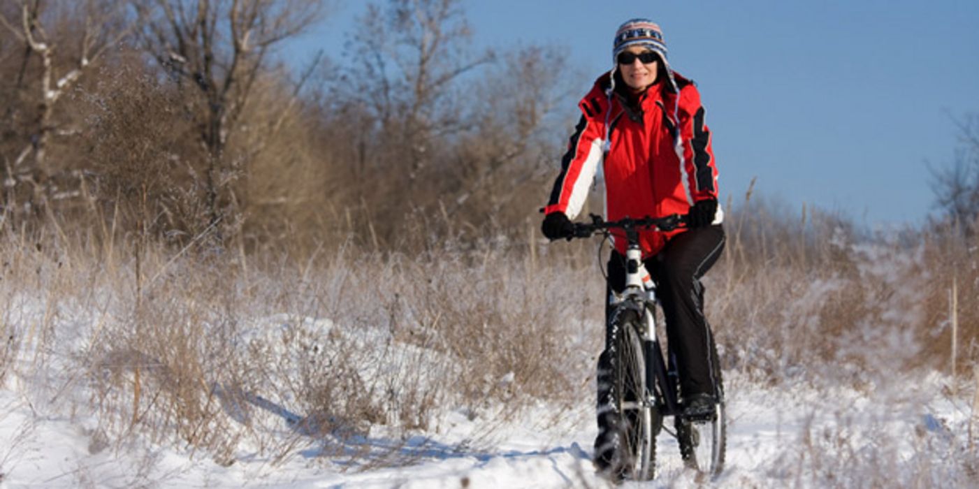 Fahrradfahrerin in winterlicher Landschaft