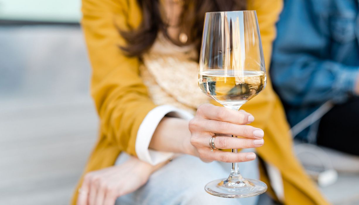 Frau, hält ein Glas Wein in der Hand.
