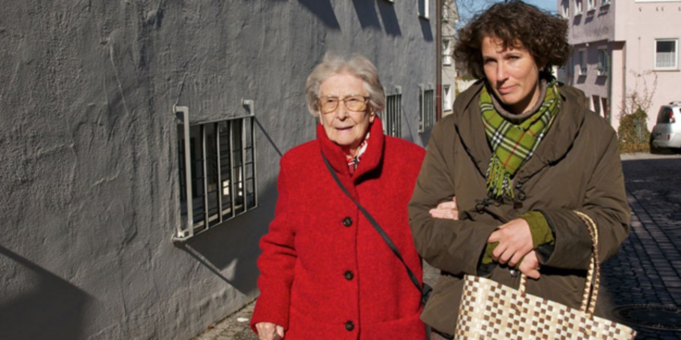 Alte Frau mit Pflegerin auf der Straße