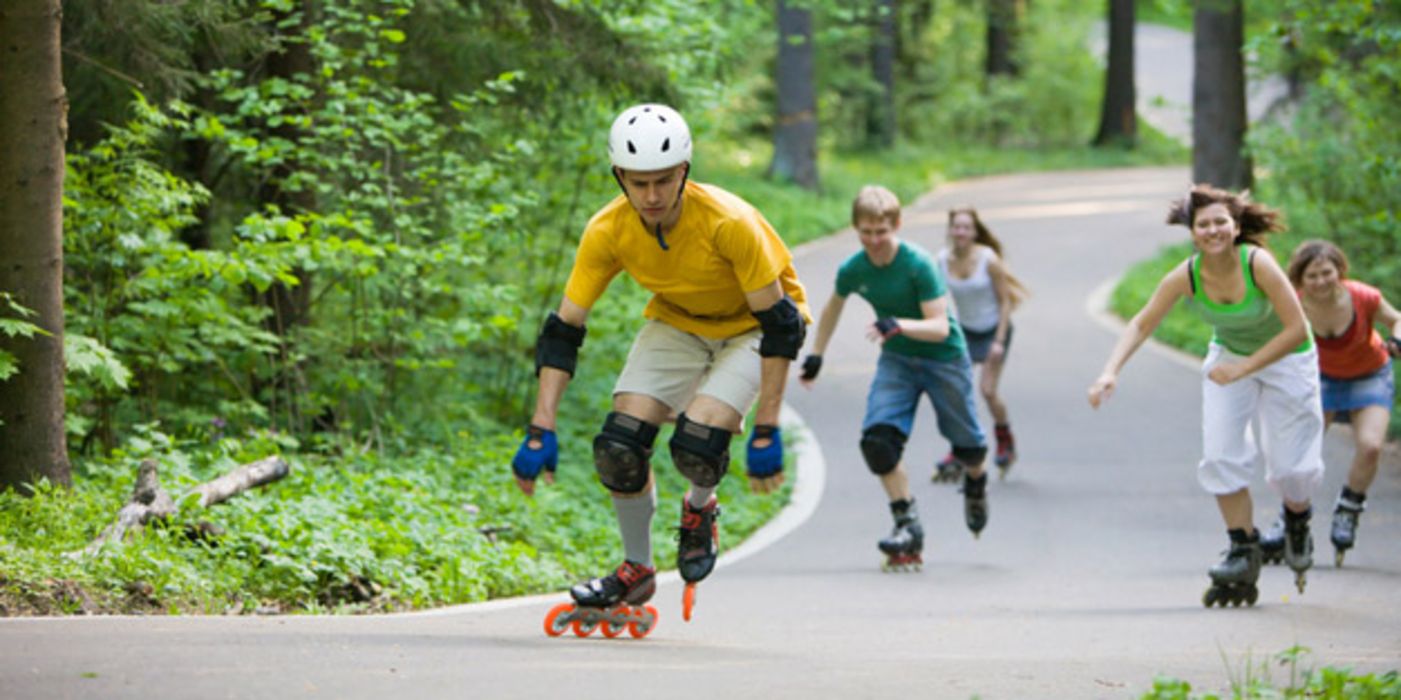 Gruppe von Inline-Skatern auf einer Straße im Wald