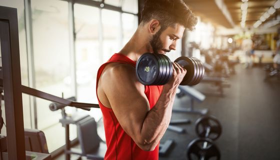 Mann, im Fitnessstudio, nutzt eine Hantel.