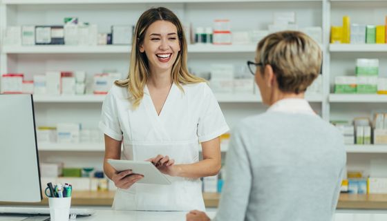 Apothekerin berät eine ältere Kundin freudestrahlend.