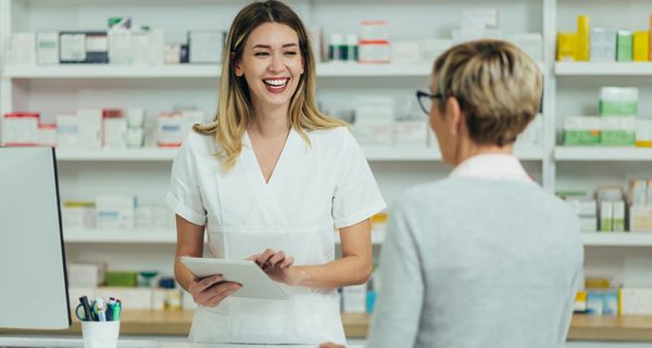 Apothekerin berät eine ältere Kundin freudestrahlend.