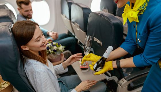 Reisende bekommt von Stewardess Sekt serviert.
