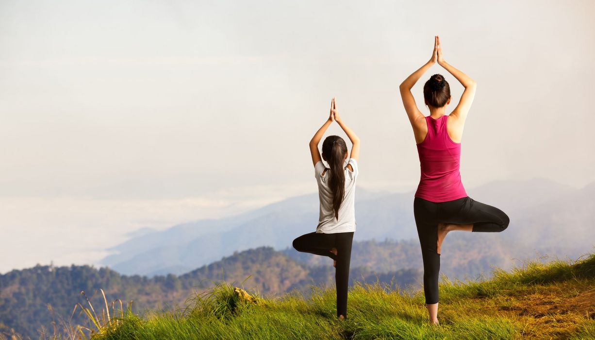 Frau und Kind, machen eine Yoga-Übung.