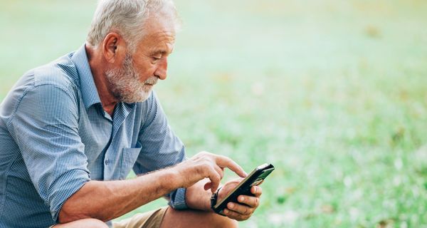 Älterer Mann, tippt auf Smartphone.