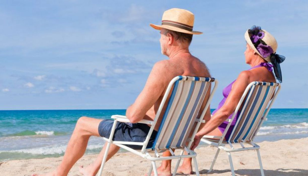 Paar sitzt mit Stühlen am Strand