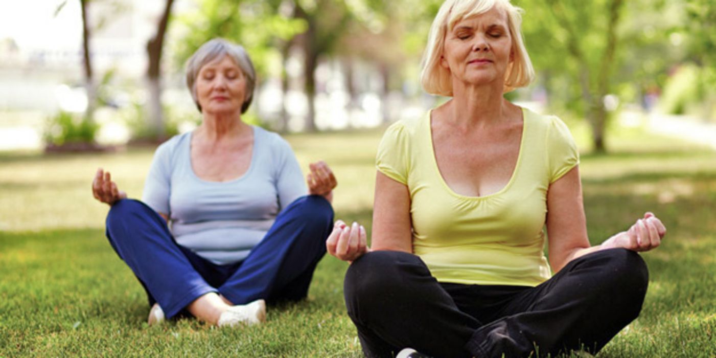 Zwei ältere Frauen meditieren im Park